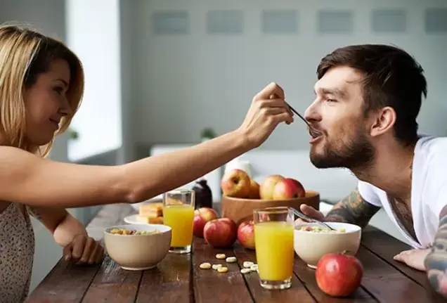 Eine Frau füttert einen Mann mit Nüssen, um die Potenz zu steigern